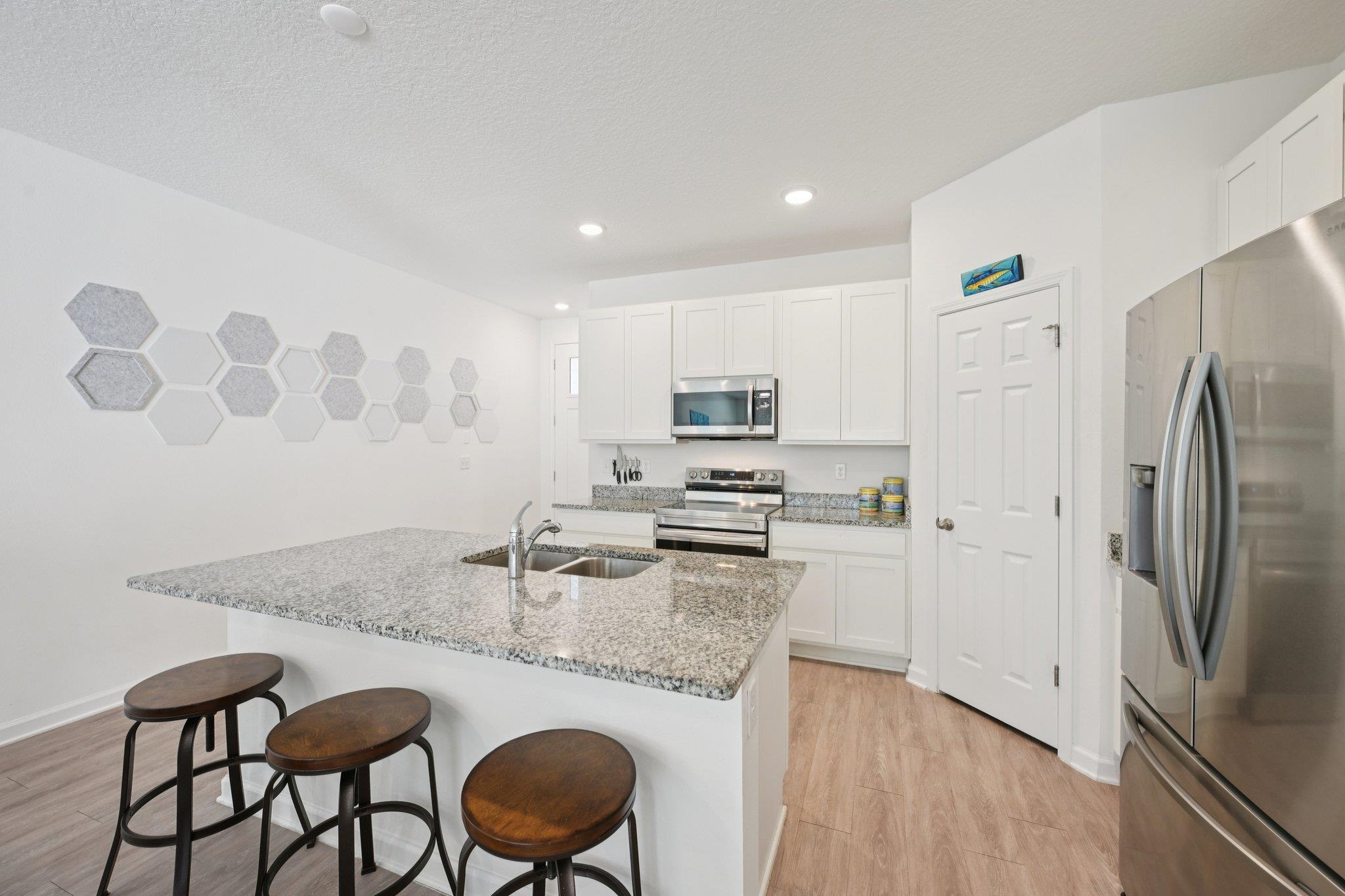 22 Ridge Lake Road St. Augustine, FL 32086 - Photo 6 of 31 Kitchen with stainless steel appliances, light stone countertops, white cabinetry, a breakfast bar area, and light wood-type flooring