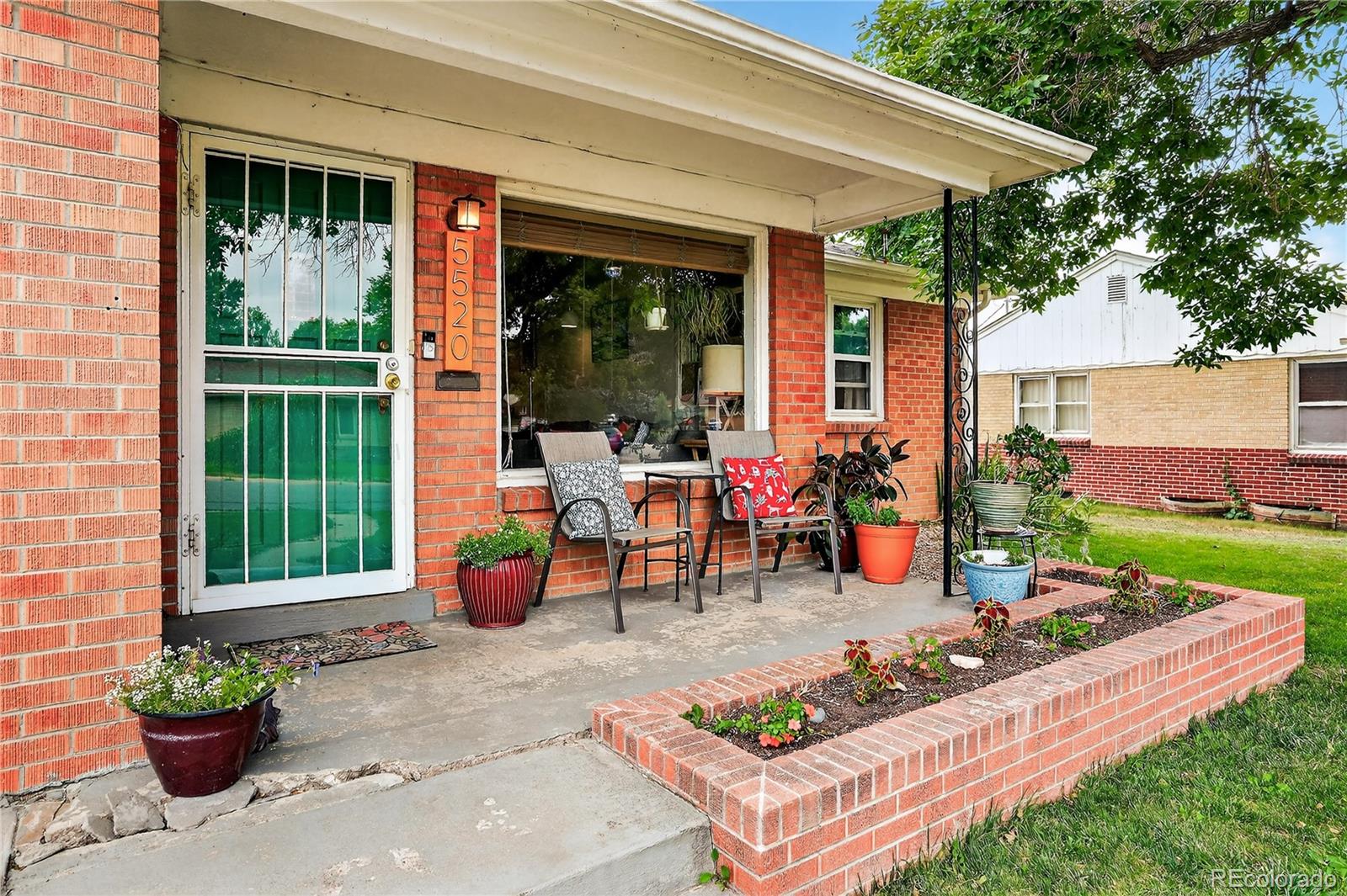 a view of a patio with table and chairs potted plants and floor to ceiling window