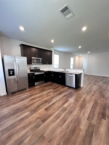 a large kitchen with stainless steel appliances a refrigerator and a microwave