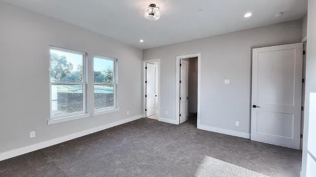 a view of an empty room with wooden floor and window