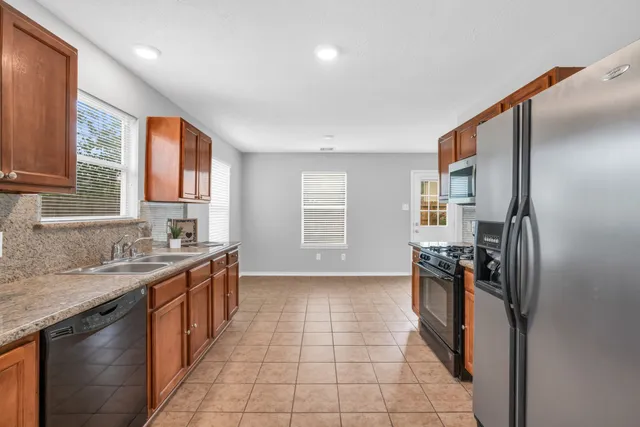 a kitchen with stainless steel appliances granite countertop a refrigerator a sink a stove and island