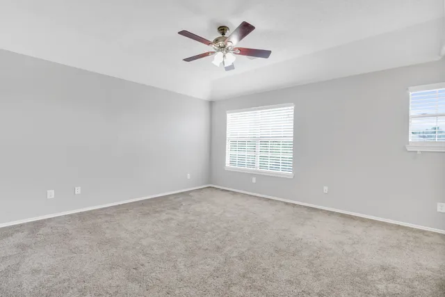 an empty room with ceiling fan and window