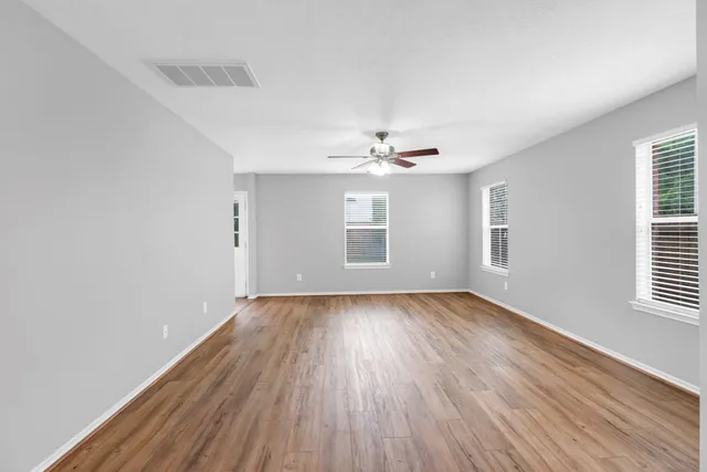 a view of an empty room with wooden floor and a window