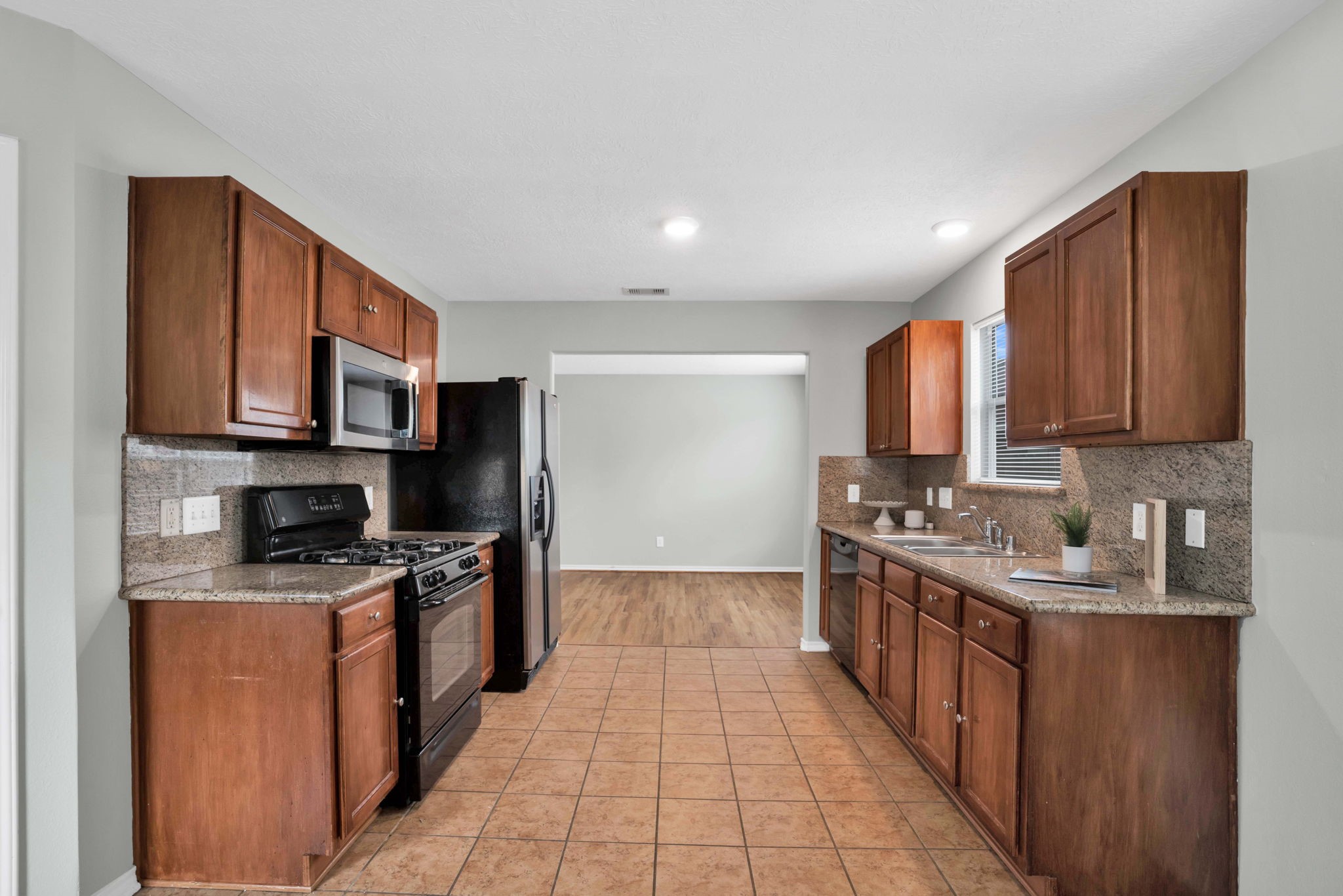 7215 Cool Spring Court Magnolia, TX 77354 - Photo 10 of 23 a kitchen with stainless steel appliances granite countertop a stove top oven a sink dishwasher and a refrigerator with wooden cabinets