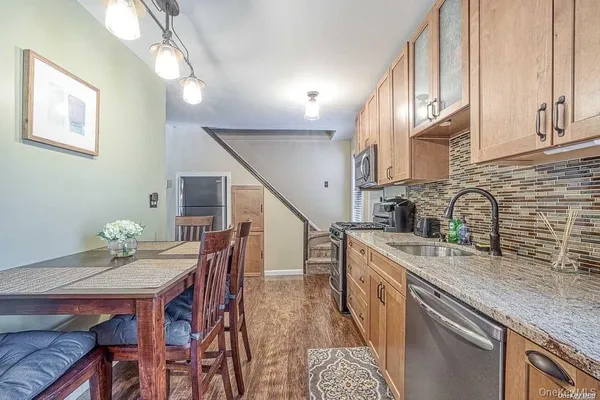 a kitchen with stainless steel appliances granite countertop a sink a stove a dining table and chairs