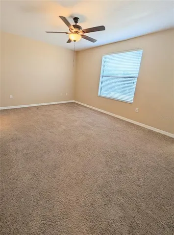 an empty room with a window and a ceiling fan
