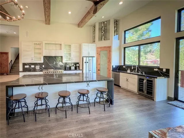 a kitchen with stainless steel appliances granite countertop a stove top oven a sink a dining table and chairs with wooden floor