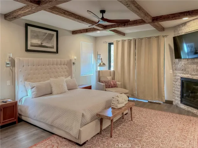 a large white bed sitting in a spacious bedroom next to a window and a fireplace
