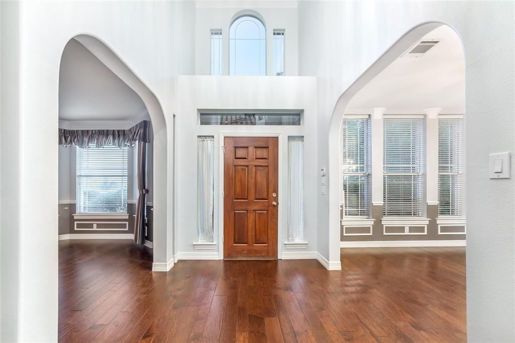5801 Yeary Road Plano, TX 75093 - Photo 3 of 33 Two-story foyer featuring a paneled wood-finish entry door with transom and sidelight windows, arched doorways, and wood-finish flooring