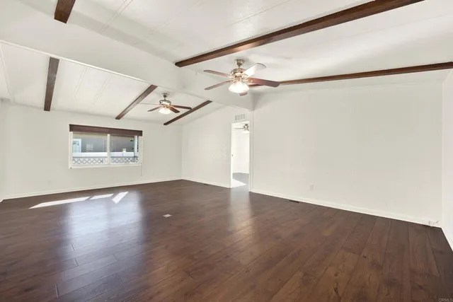a view of a big room with wooden floor and windows