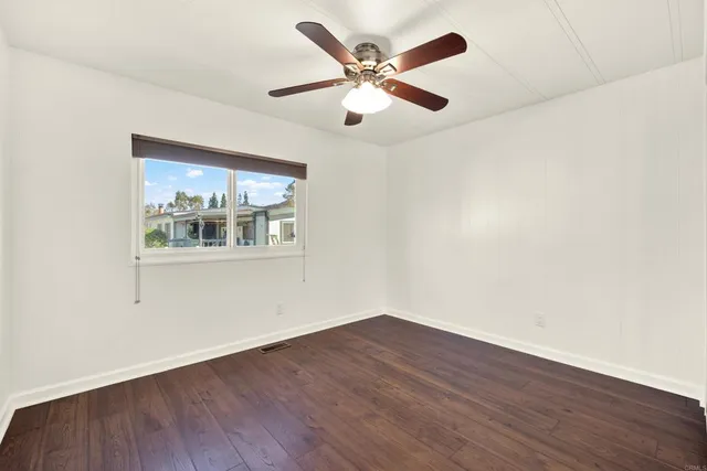 an empty room with wooden floor and ceiling fan