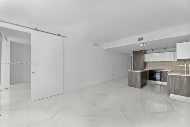 an empty room with stainless steel appliances wooden cabinet and windows