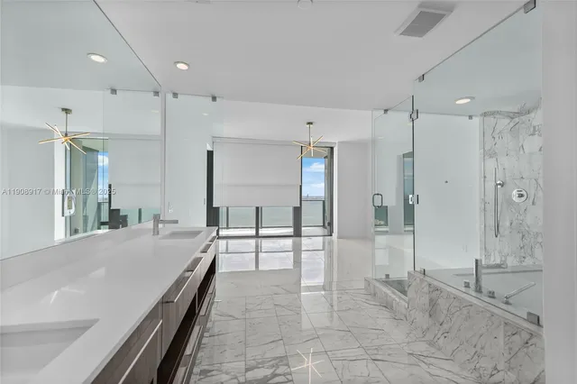 a large en suite bathroom with a granite countertop sink mirror and shower