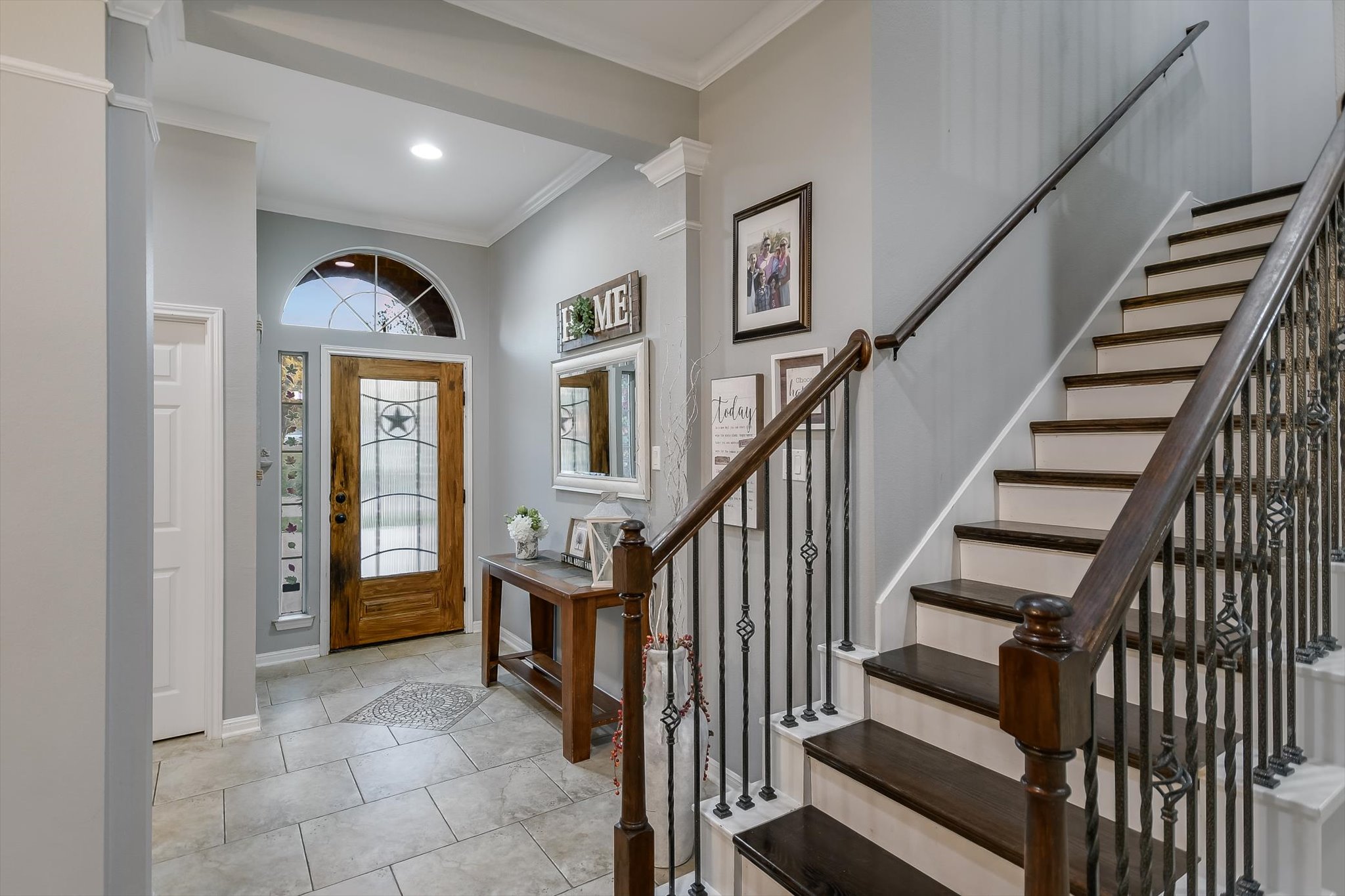 300 Wesley Ridge Drive Spicewood, TX 78669 - Photo 7 of 40 The entryway sets an inviting tone with its detailed iron-accented front door, high ceilings, and a staircase featuring elegant wrought iron balusters - leading to the game room.