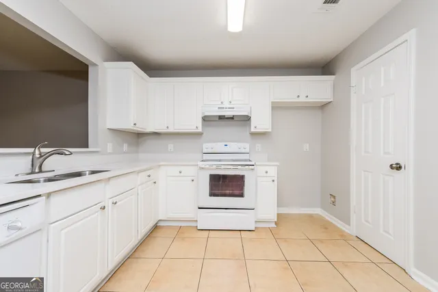 a kitchen with granite countertop white cabinets and appliances