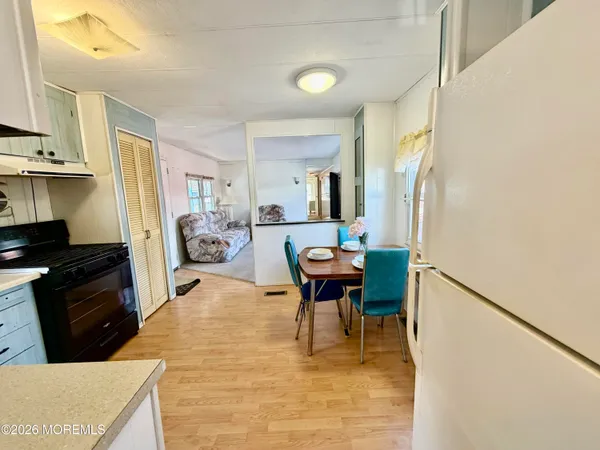 a living room with stainless steel appliances furniture a fireplace and a kitchen view