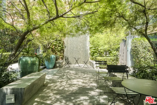 a view of a patio with table and chairs and potted plants with large trees