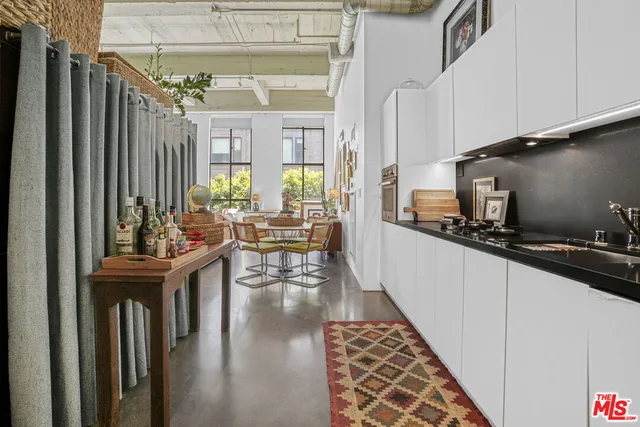 a kitchen with stainless steel appliances granite countertop a refrigerator a sink dishwasher a stove and white countertops with wooden floor