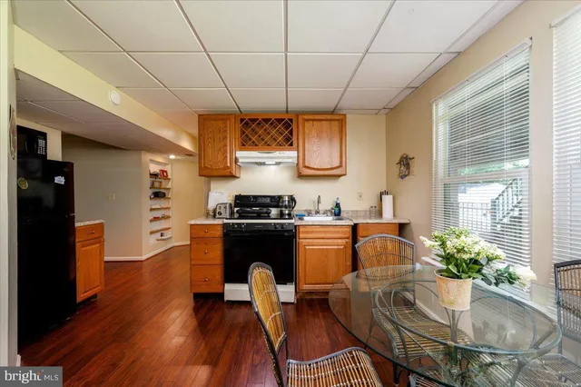 a kitchen with stainless steel appliances granite countertop a stove a refrigerator a sink a dining table and chairs with wooden floor