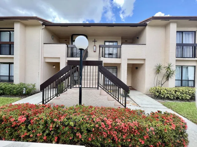a view of a patio with table and chairs potted plants and palm trees