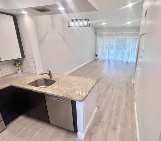 a kitchen with stainless steel appliances granite countertop a sink dishwasher and a stove with wooden floor