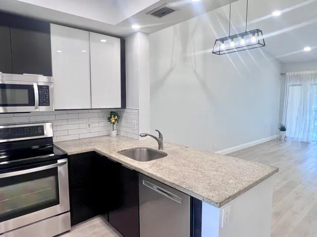 a kitchen with a sink dishwasher a stove and a microwave oven with white cabinets