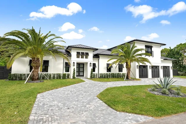 a view of a white house with a big yard and potted plants