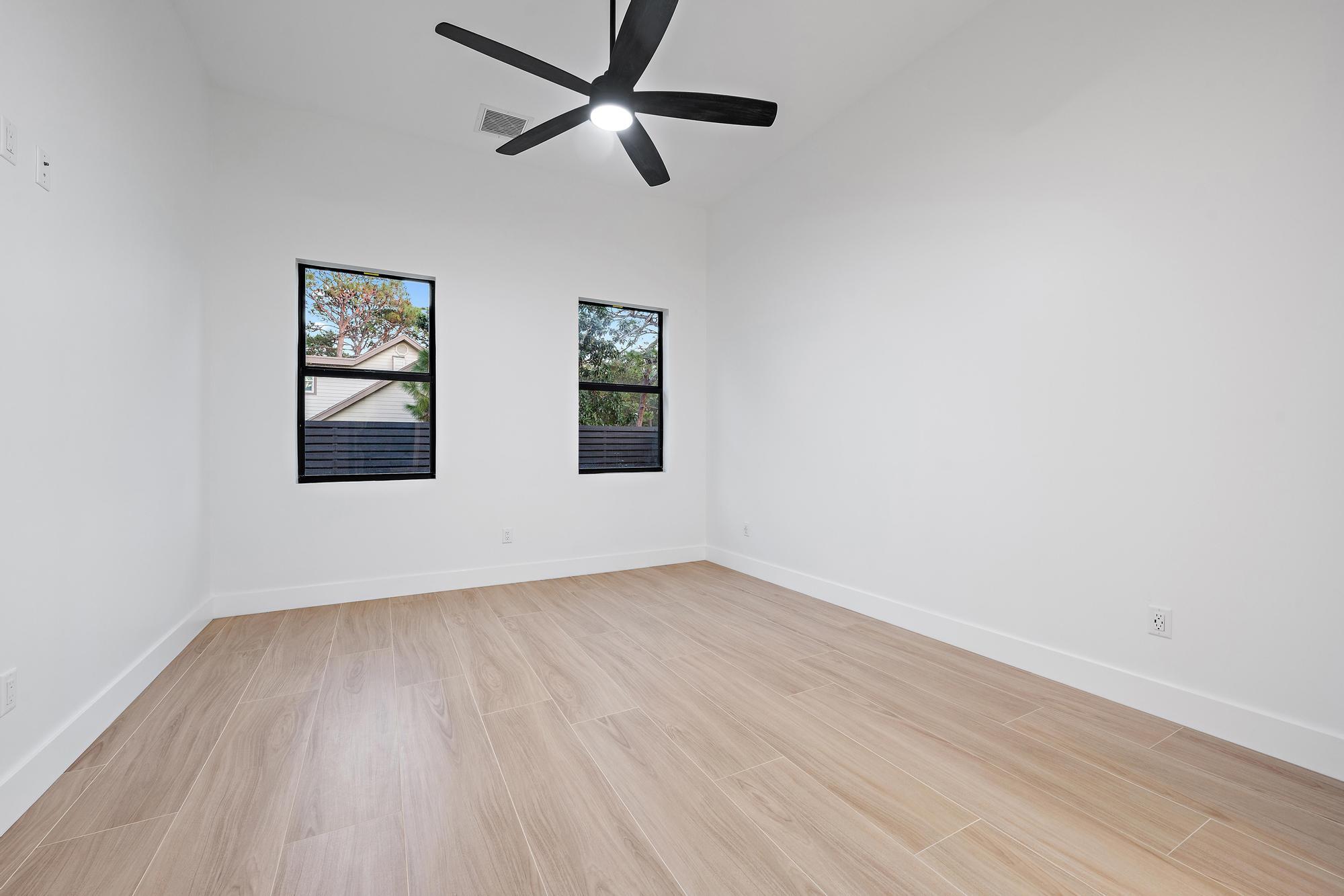 5701 Old Orange Road Jupiter, FL 33458 - Photo 33 of 51 an empty room with wooden floor ceiling fan and windows