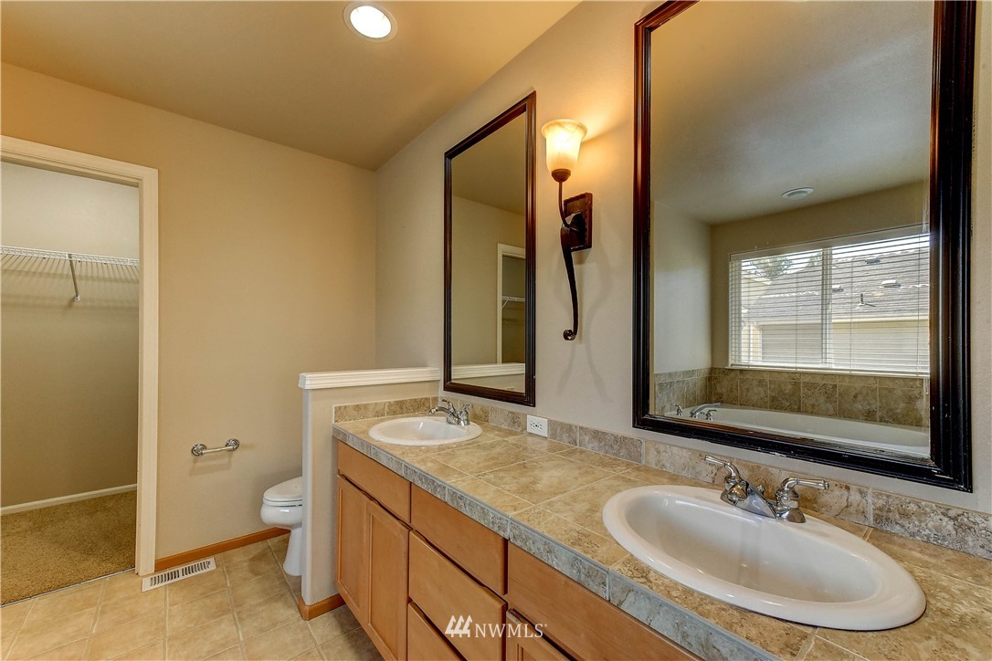 1716 235th Place Southwest Bothell, WA 98021 - Photo 16 of 25 a bathroom with a granite countertop sink a toilet a mirror and shower