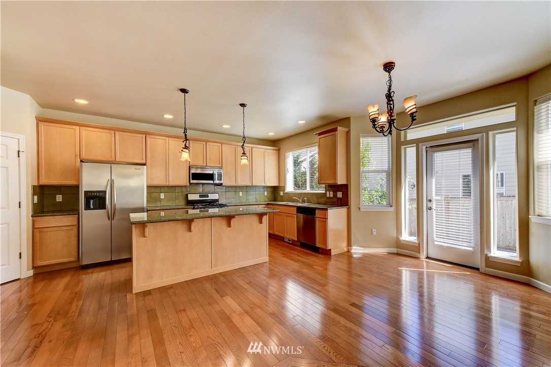 1716 235th Place Southwest Bothell, WA 98021 - Photo 9 of 25 a kitchen with stainless steel appliances kitchen island granite countertop a refrigerator a oven a stove and a wooden floors