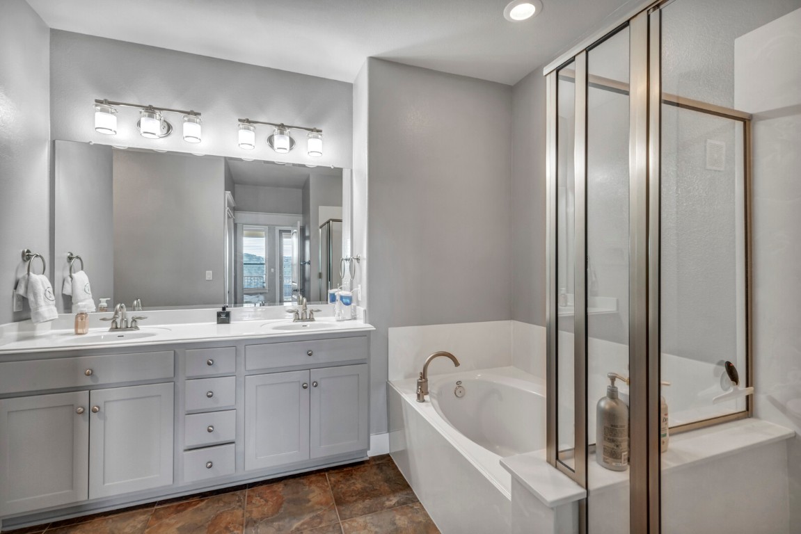 17808 Maritime Point, Unit 301 Jonestown, TX 78645 - Photo 14 of 40 a bathroom with a tub a double vanity sink a mirror a window and vanity