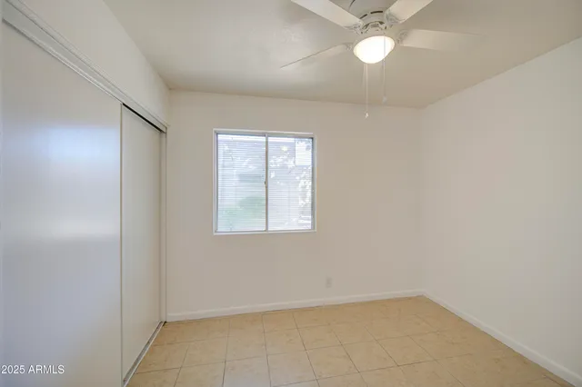 an empty room with a window and a fan