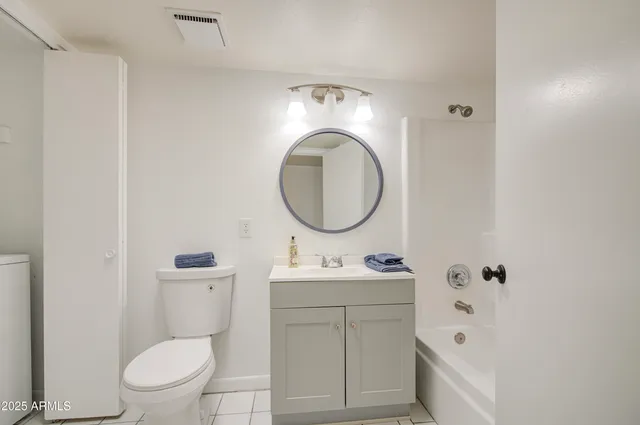 a bathroom with a toilet sink vanity tub and mirror