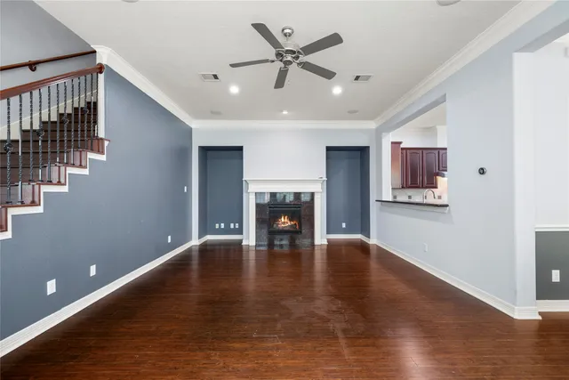 a view of a livingroom with a fireplace a ceiling fan and wooden floor