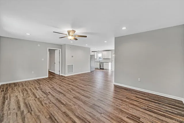 a view of an empty room with a window and wooden floor