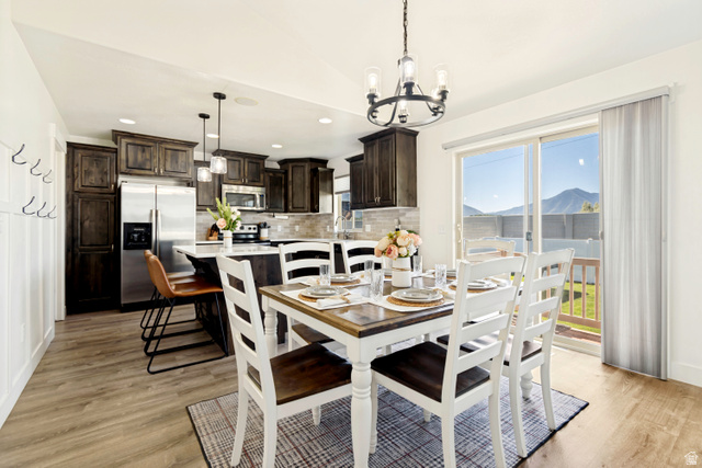 983 West 1550th Street South Springville, UT 84663 - Photo 15 of 43 Open-concept dining area featuring wood-finish flooring, a contemporary chandelier, and direct patio access through sliding glass doors.