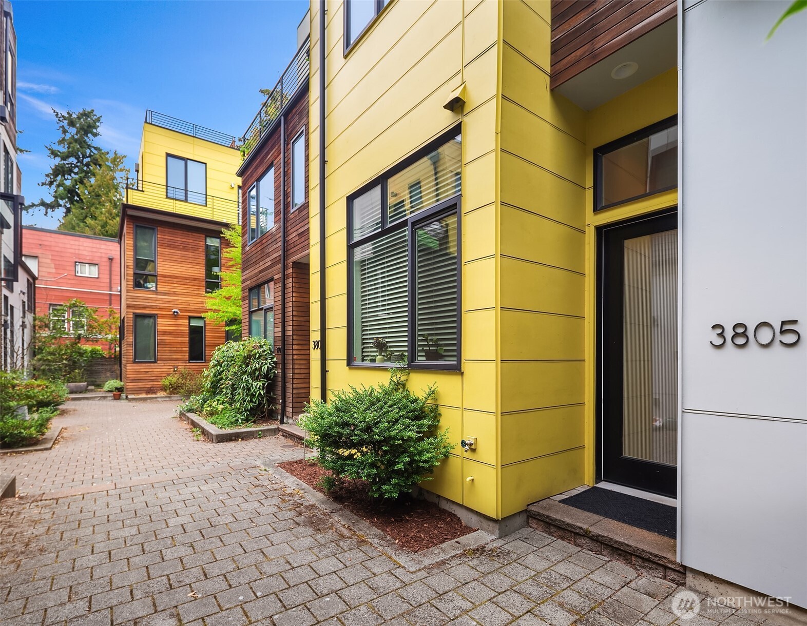 a view of a brick house with a large window and flower plants