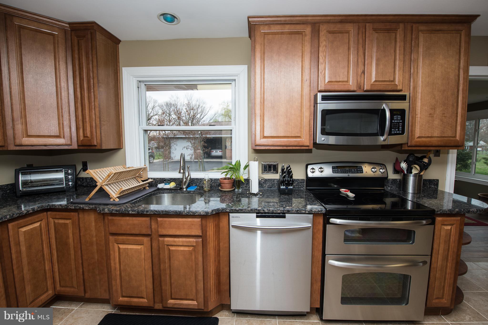 604 Bryan Point Road Accokeek, MD 20607 - Photo 3 of 29 a kitchen with granite countertop a stove a microwave a sink and cabinets