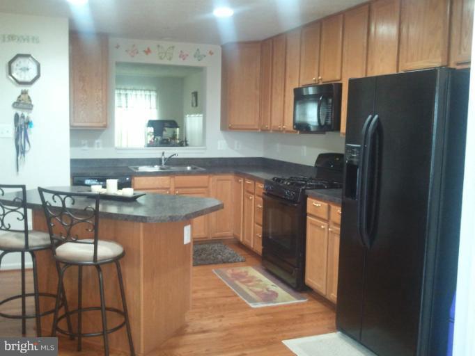 9902 Decatur Road Middle River, MD 21220 - Photo 2 of 18 a kitchen with stainless steel appliances granite countertop a refrigerator a sink a stove a dining table and chairs