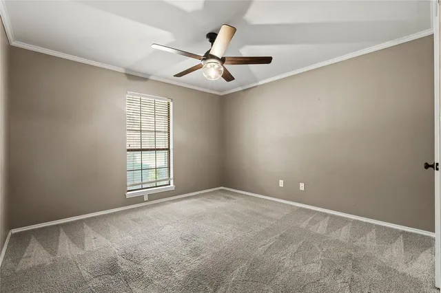 an empty room with windows and chandelier fan