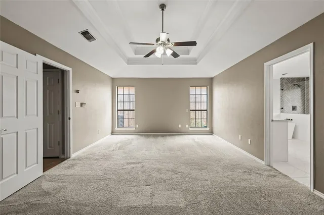an empty room with windows and ceiling fan
