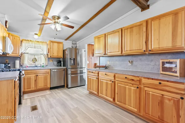 a kitchen with granite countertop a sink cabinets stainless steel appliances and a window