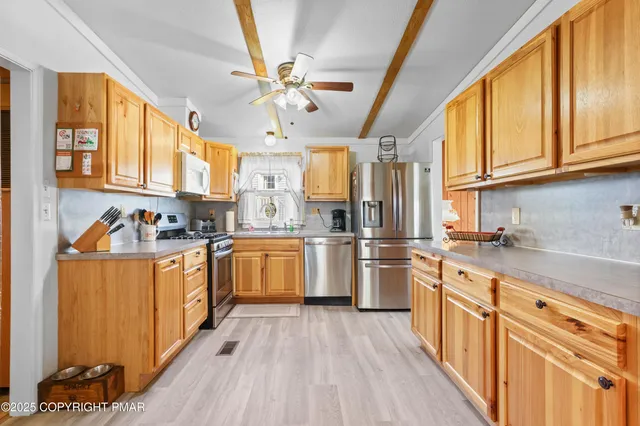 a kitchen with stainless steel appliances granite countertop a refrigerator a sink dishwasher a stove and white countertops with wooden floor