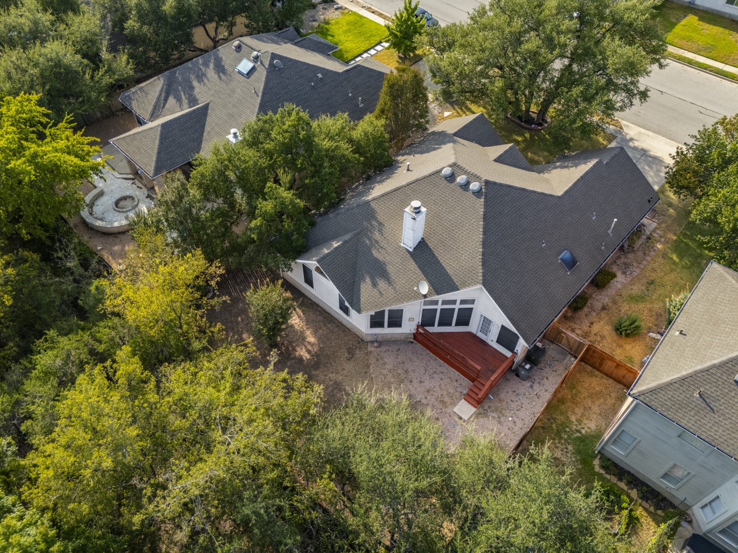 1108 Antelope Ridge Cedar Park, TX 78613 - Photo 30 of 39 Mature trees surround a private backyard featuring a wooden deck and shingled rooflines.