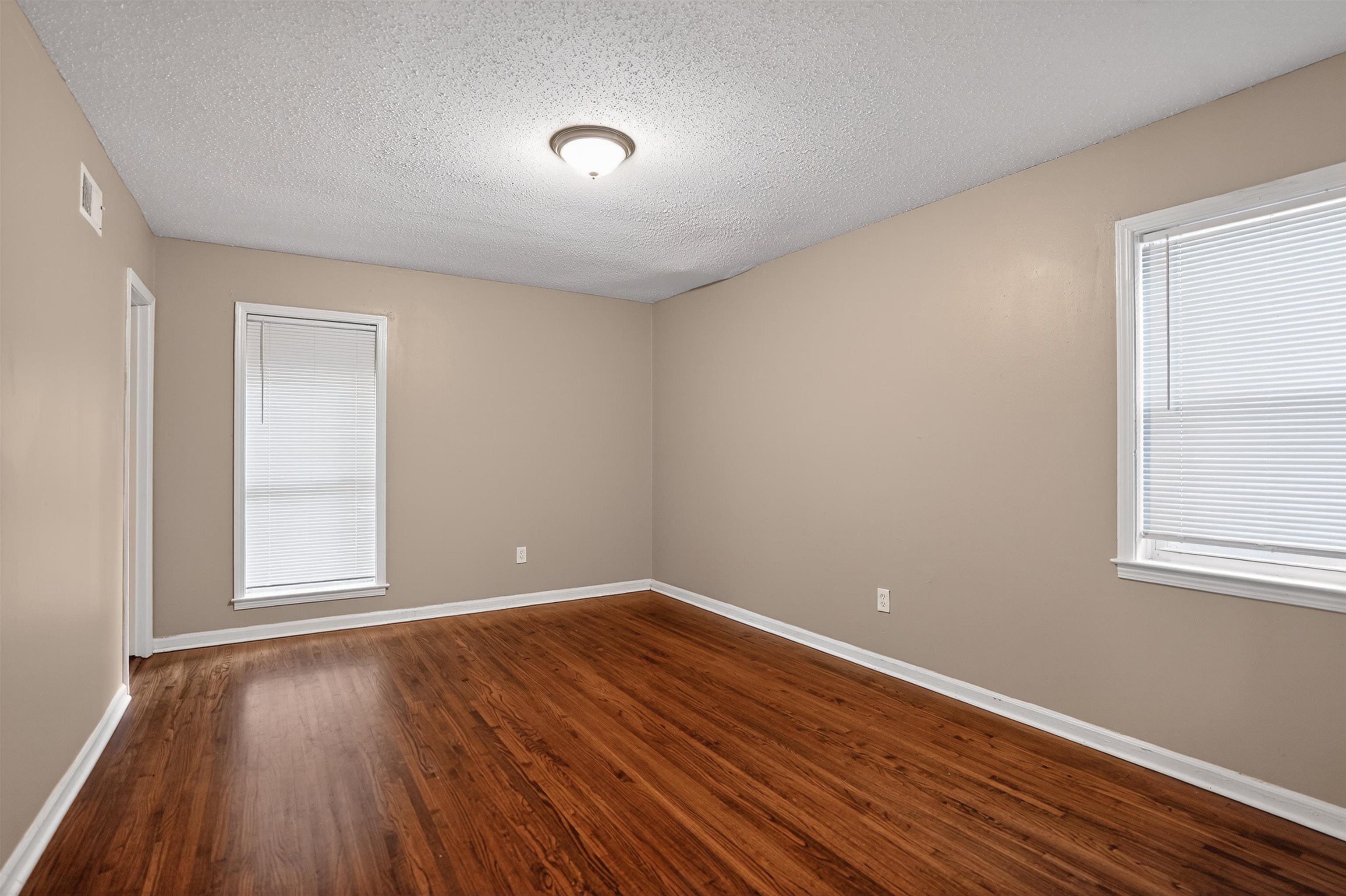 4191 Yale Road Memphis, TN 38128 - Photo 8 of 22 Spacious room featuring rich wood-finish flooring, neutral wall tones, two windows with blinds, a ceiling-mounted light fixture, and white baseboards