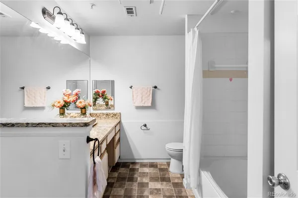a spacious bathroom with a granite countertop sink a toilet and a mirror