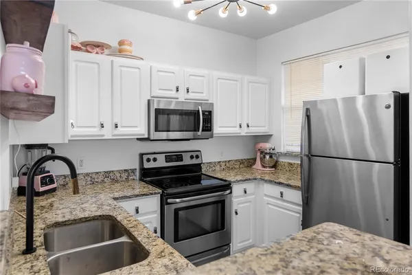 a kitchen with granite countertop a refrigerator stove and sink