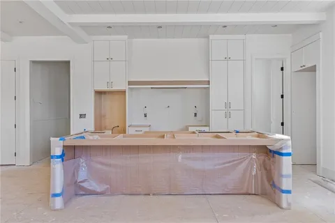 a room with kitchen island stainless steel appliances a sink and cabinets