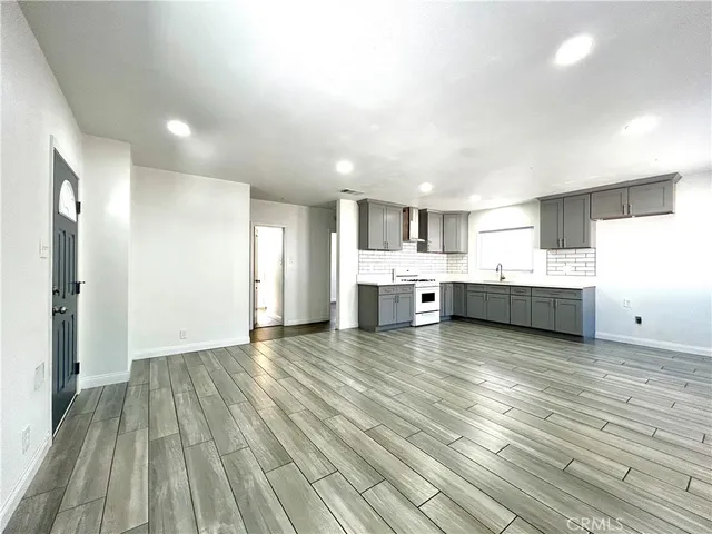 a view of a kitchen with kitchen island wooden floors stainless steel appliances and cabinets