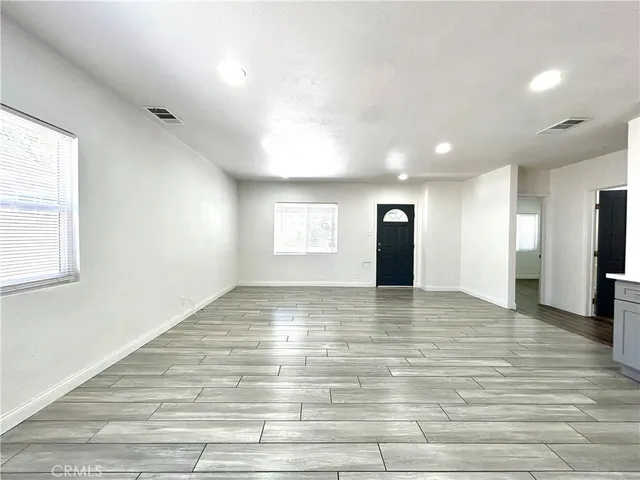 a view of an empty room with window and wooden floor